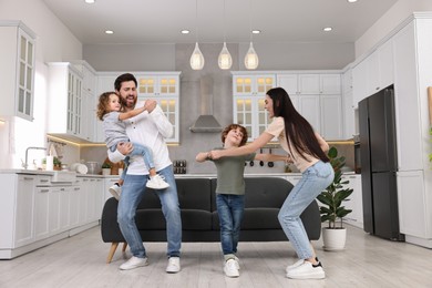 Happy family dancing and having fun at home, low angle view