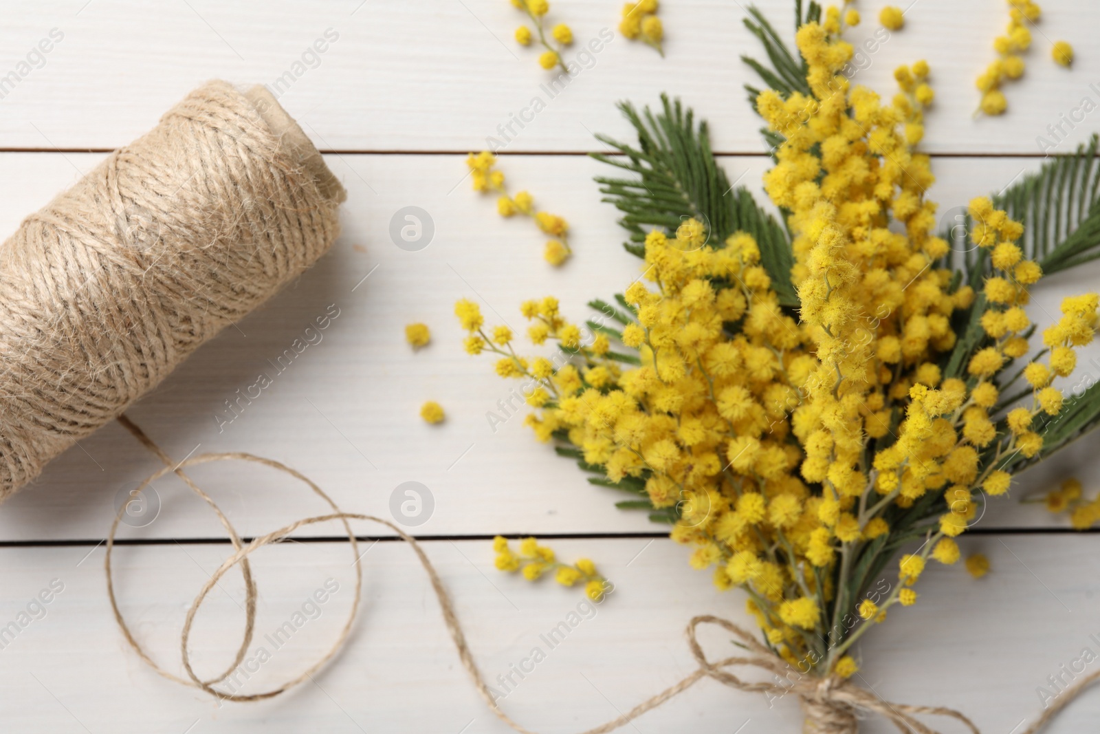 Photo of Beautiful mimosa flowers and twine on white wooden table, flat lay