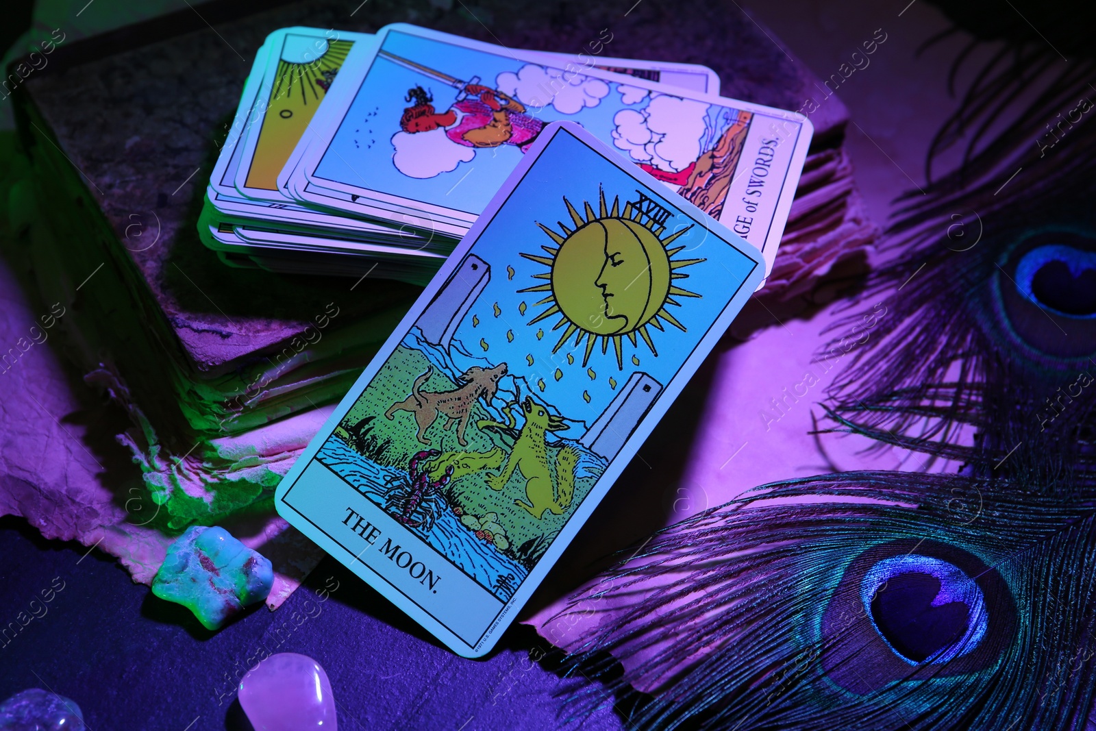 Photo of Moon and other tarot cards with old book on dark table, color toned