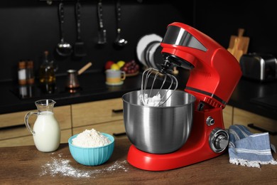 Modern red stand mixer and ingredients on wooden table in kitchen