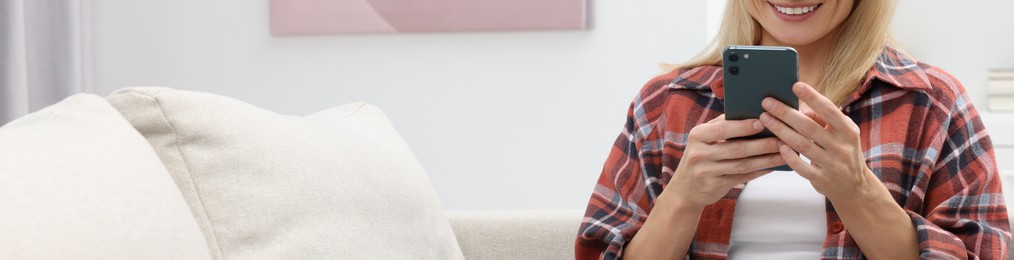 Image of Woman typing message on mobile phone indoors, closeup. Banner design with space for text