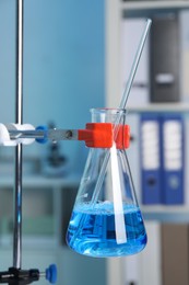 Laboratory analysis. Glass flask with blue liquid on stand indoors, closeup