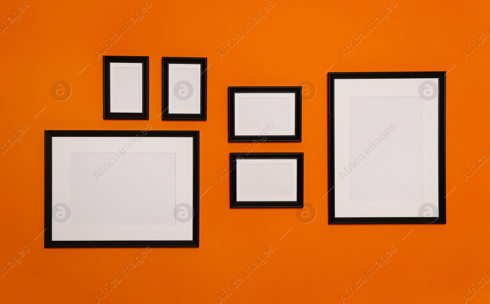 Photo of Empty frames hanging on orange wall. Mockup for design