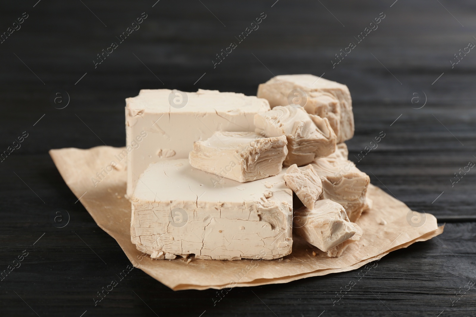 Photo of Pieces of compressed yeast on black wooden table