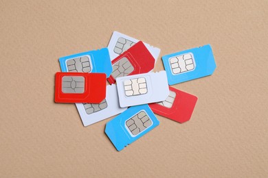 Pile of different SIM cards on beige background, flat lay