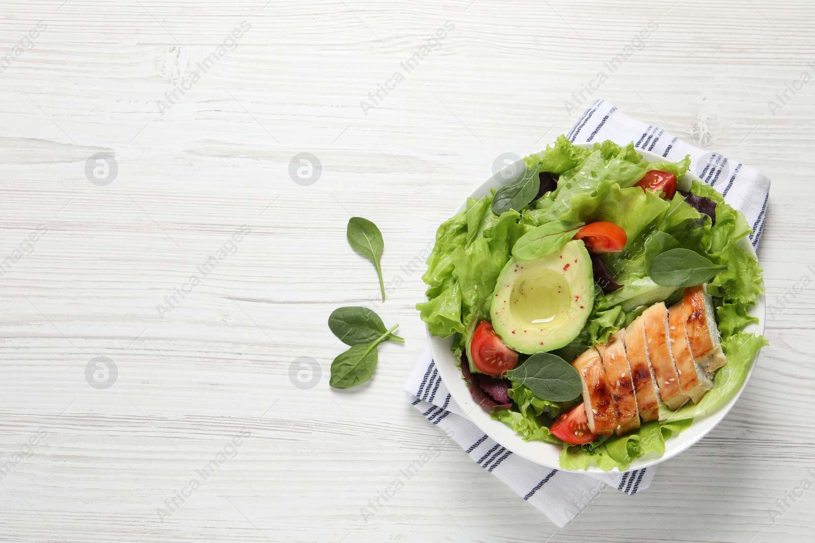 Photo of Delicious salad with chicken, cherry tomato and avocado on white wooden table, top view. Space for text