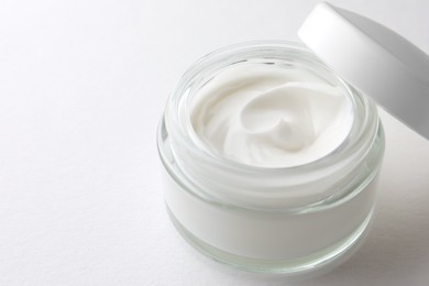 Jar of face cream on white background, closeup. Space for text