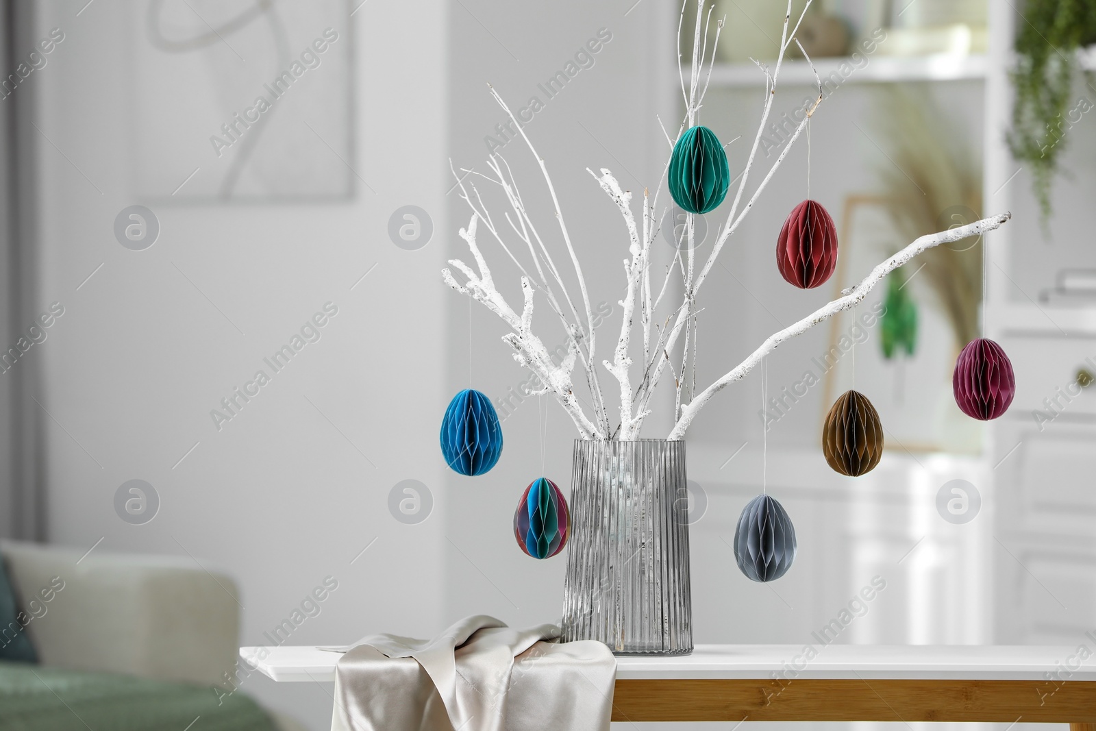 Photo of Branches with paper eggs in vase on white table at home, space for text. Beautiful Easter decor