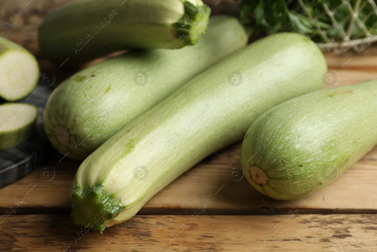 Photo of Raw green zucchinis on wooden table, closeup