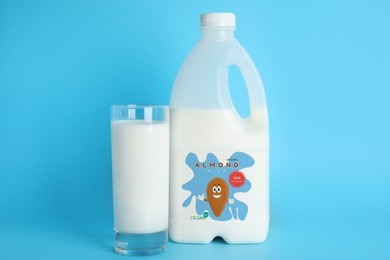 Image of Gallon bottle and glass of almond milk on light blue background. Vegan product