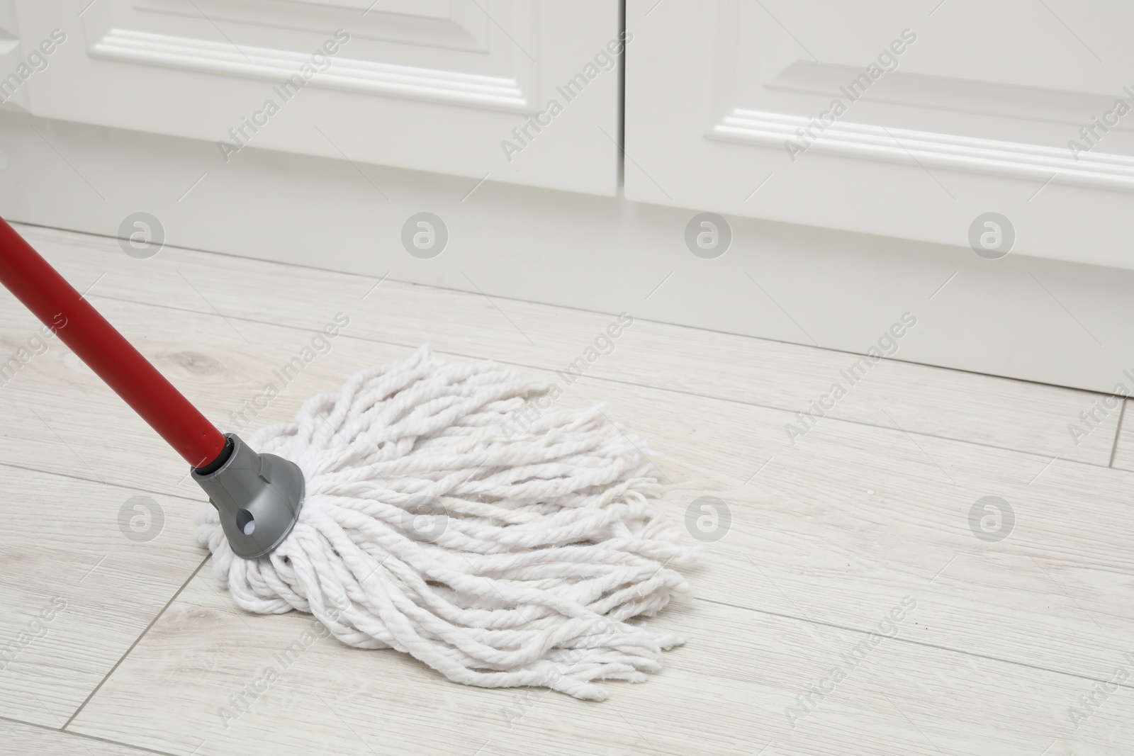 Photo of Cleaning white parquet floor with mop, closeup