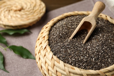 Photo of Wicker box with chia seeds and scoop on table, closeup