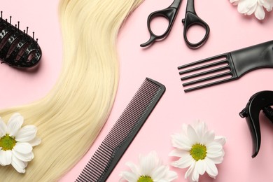 Flat lay composition with different hairdresser tools and flowers on pink background