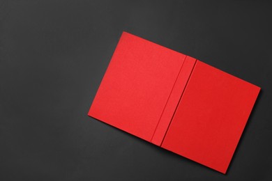 Photo of Book with red cover on black background, top view. Space for text