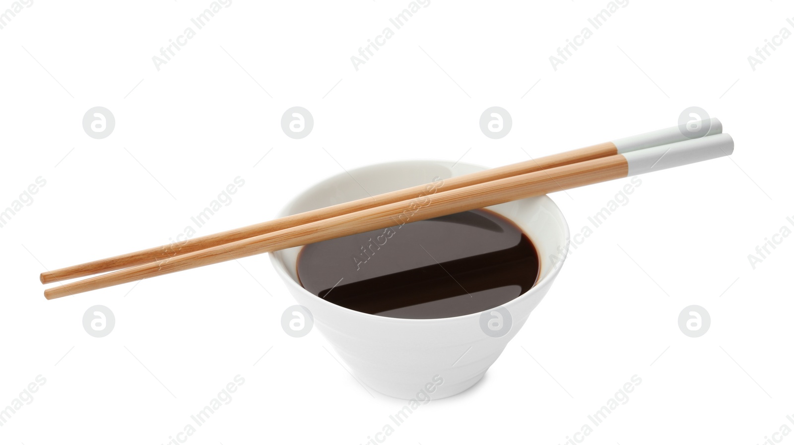 Photo of Bowl of soy sauce and chopsticks on white background