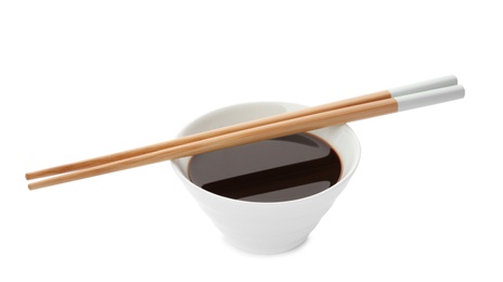 Bowl of soy sauce and chopsticks on white background