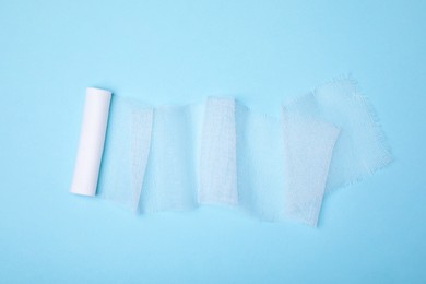White medical bandage on light blue background, top view