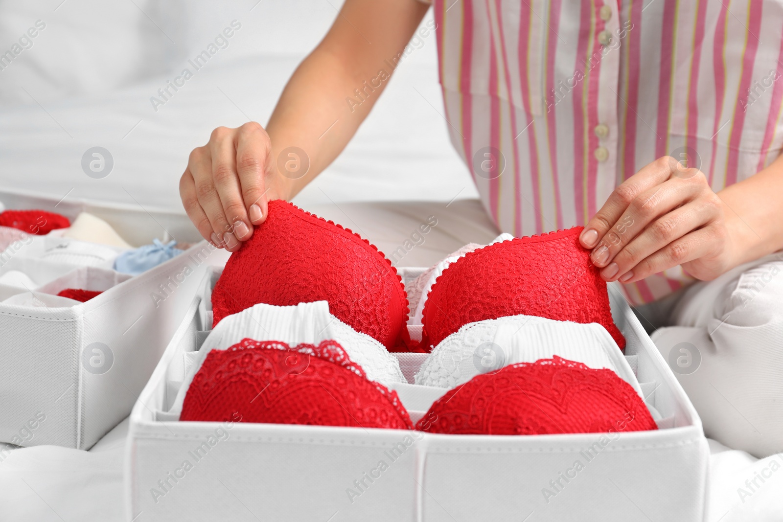 Photo of Woman putting underwear into organizer on bed, closeup