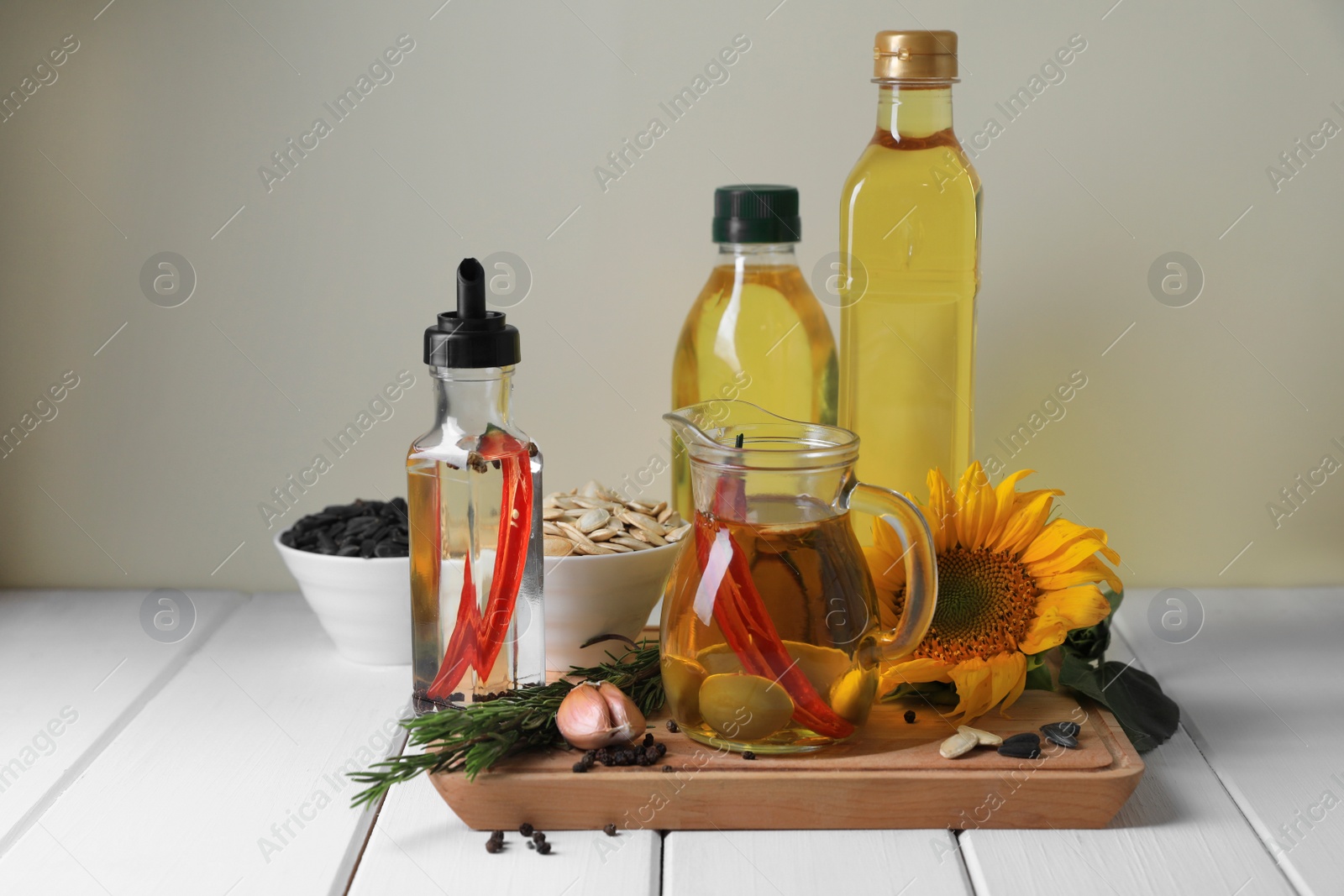 Photo of Different cooking oils and ingredients on white wooden table against light background