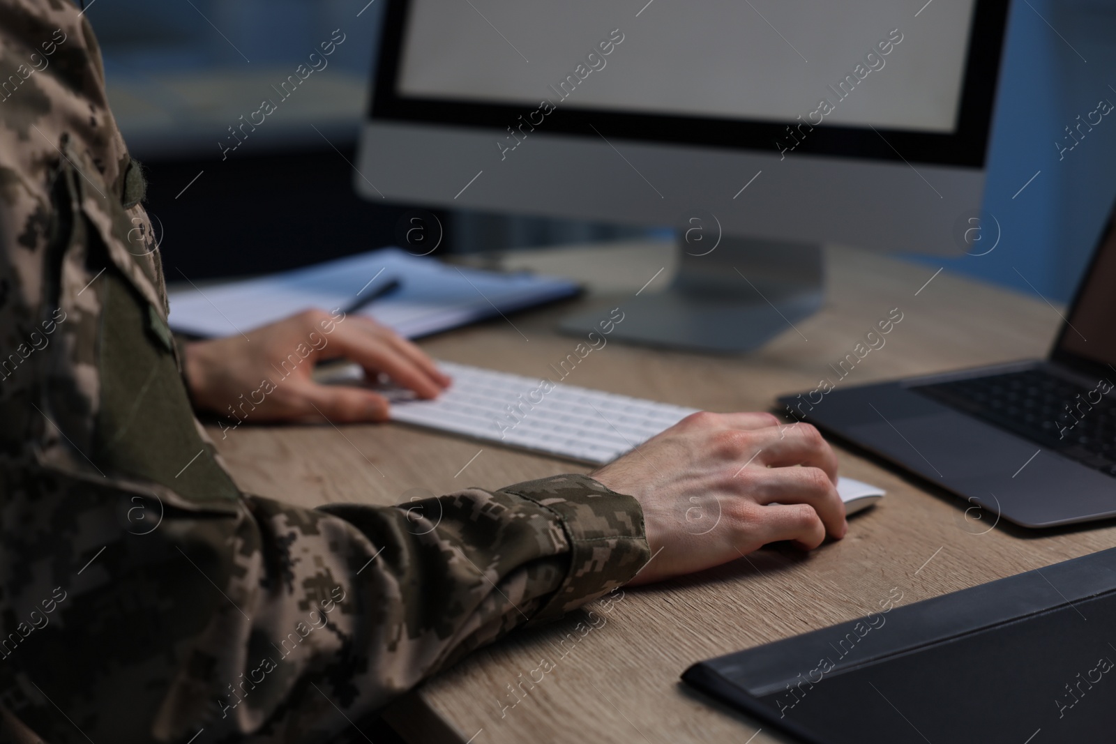 Photo of Military service. Soldier working at wooden table indoors, closeup