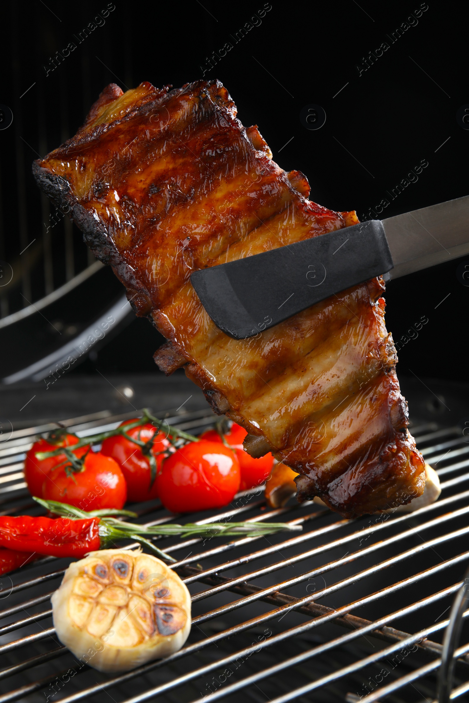 Photo of Delicious ribs and vegetables on barbecue grill