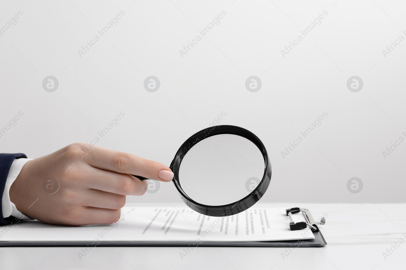 Photo of Woman looking at document through magnifier at white table, closeup. Searching concept