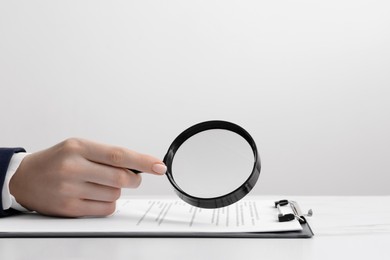 Photo of Woman looking at document through magnifier at white table, closeup. Searching concept