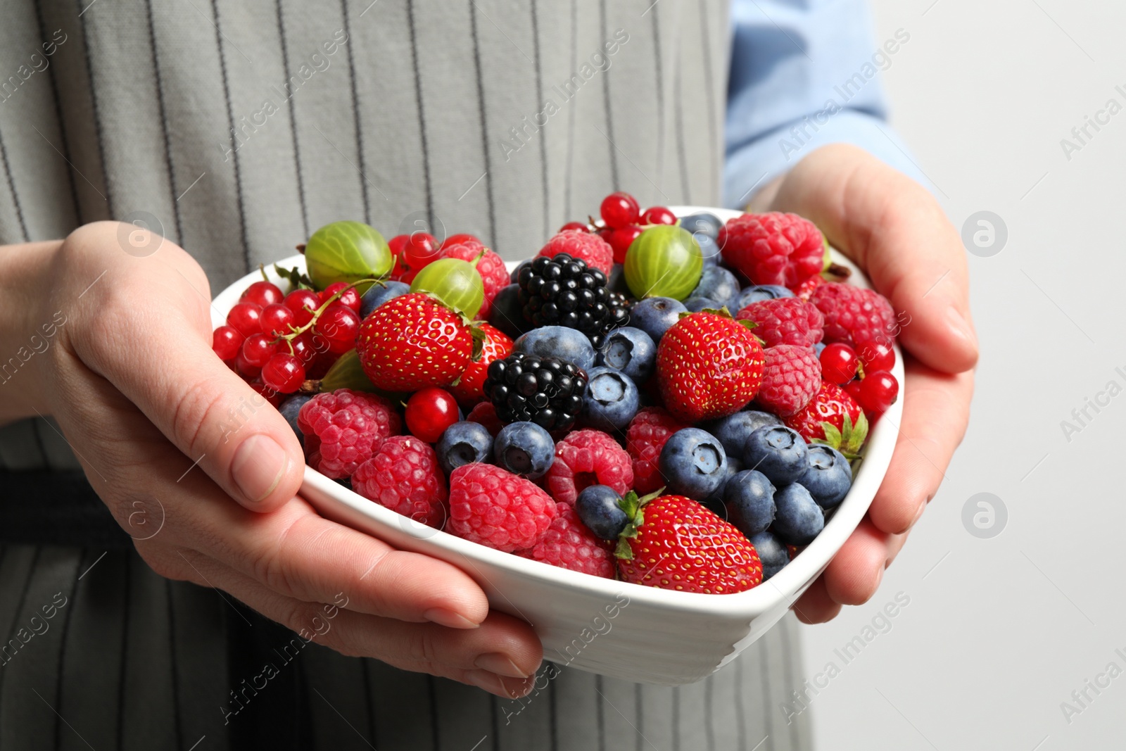 Photo of Woman with bowl of delicious summer berries, closeup