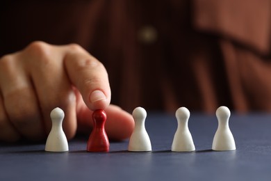 Photo of Choice concept. Woman choosing red pawn among white ones at dark blue table, closeup