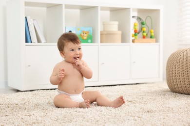 Cute baby boy sitting on carpet at home