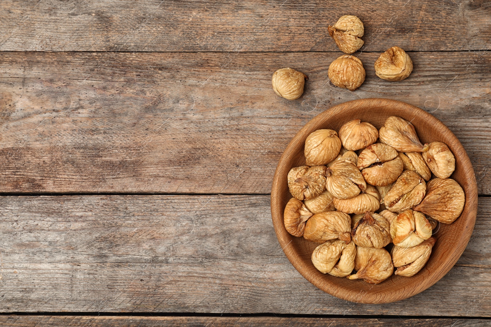 Photo of Bowl full of figs on wooden background, top view with space for text. Dried fruit as healthy food