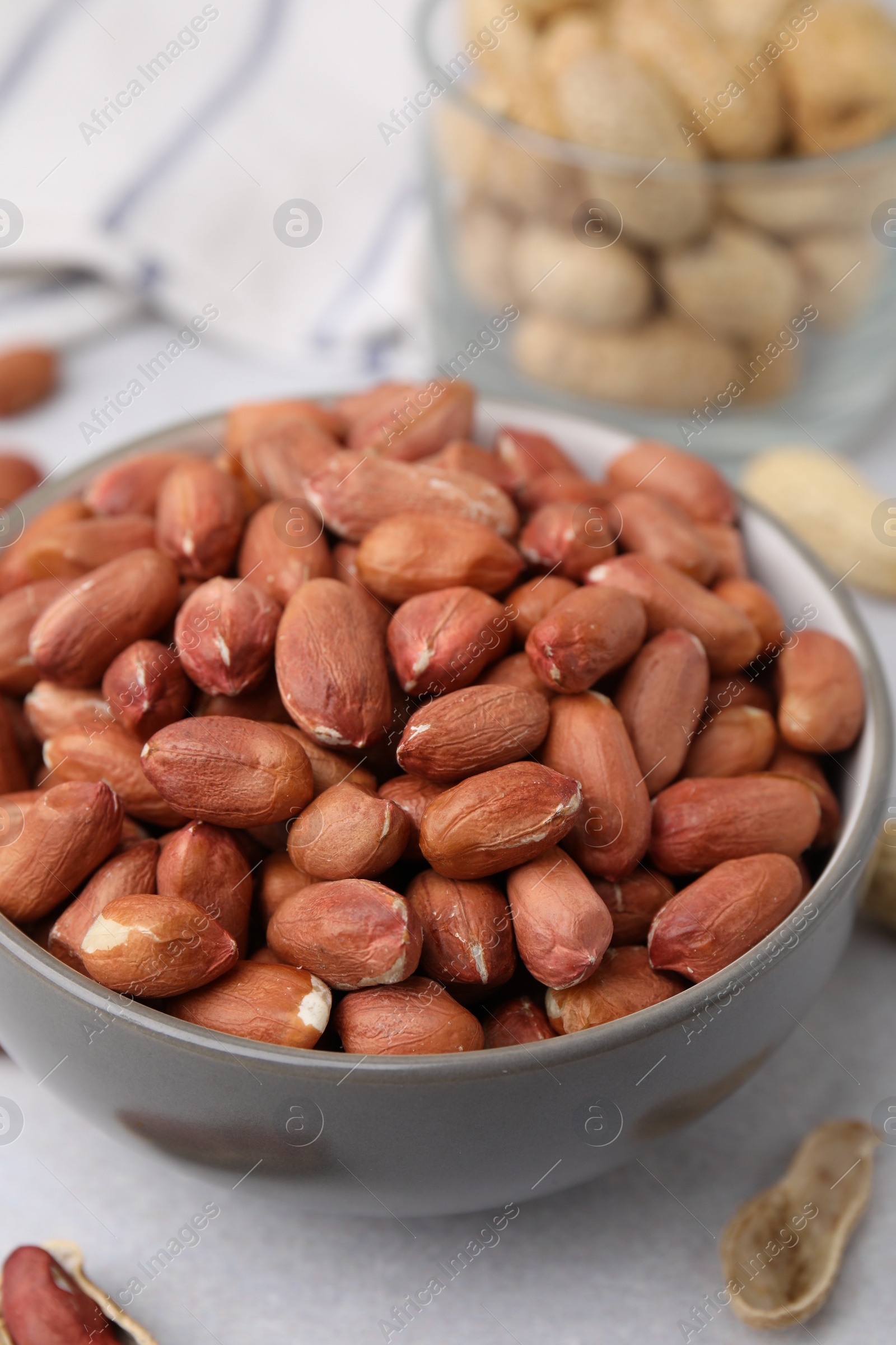 Photo of Fresh unpeeled peanuts in bowl on grey table, closeup