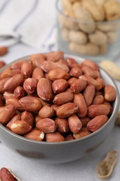 Fresh unpeeled peanuts in bowl on grey table, closeup