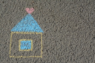 Photo of House with heart drawn by blue and yellow chalk on asphalt, top view. Space for text