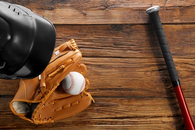 Baseball glove, bat, ball and batting helmet on wooden table, flat lay. Space for text