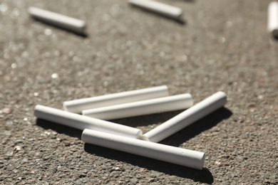 Photo of Many white chalk sticks on asphalt, closeup