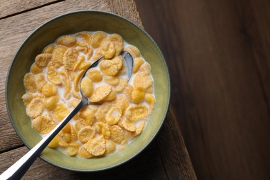 Tasty cornflakes with milk in bowl on wooden table, top view. Space for text