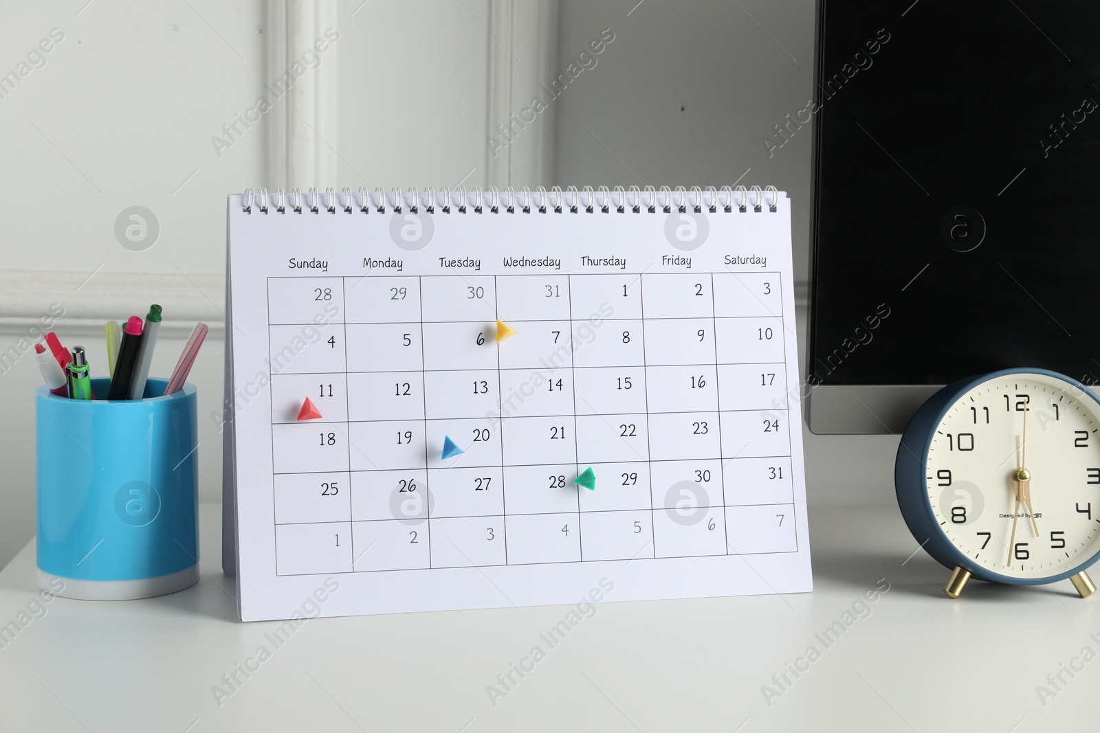 Photo of Timetable. Calendar with marked dates, alarm clock and stationery on white table indoors