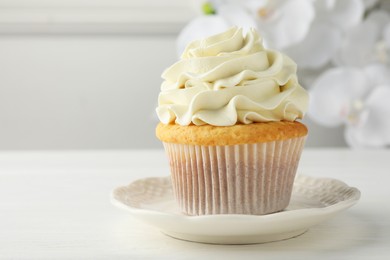 Photo of Tasty vanilla cupcake with cream on white table, closeup