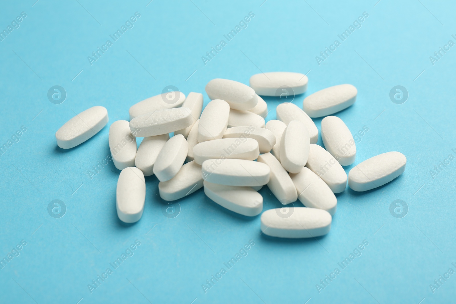 Photo of Pile of vitamin pills on light blue background