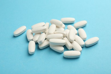 Pile of vitamin pills on light blue background