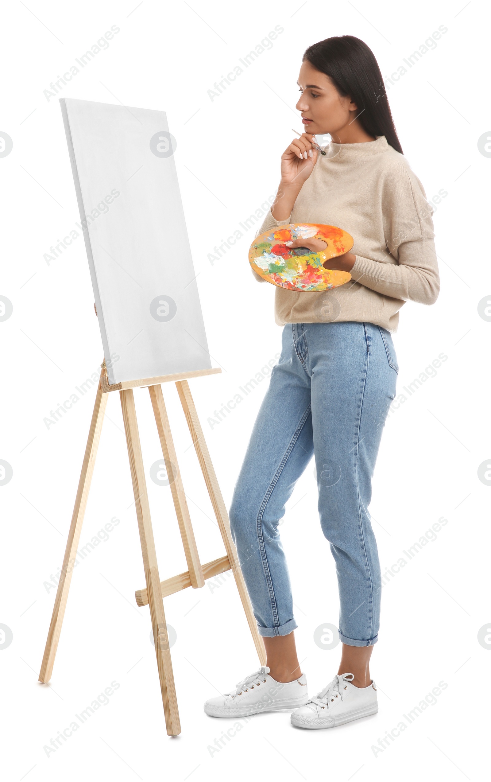 Photo of Young woman drawing on easel against white background