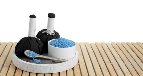 Photo of Bowl with blue sea salt and herbal bags on wooden table against white background