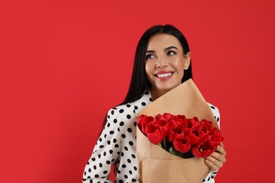 Photo of Happy woman with tulip bouquet on red background. 8th of March celebration
