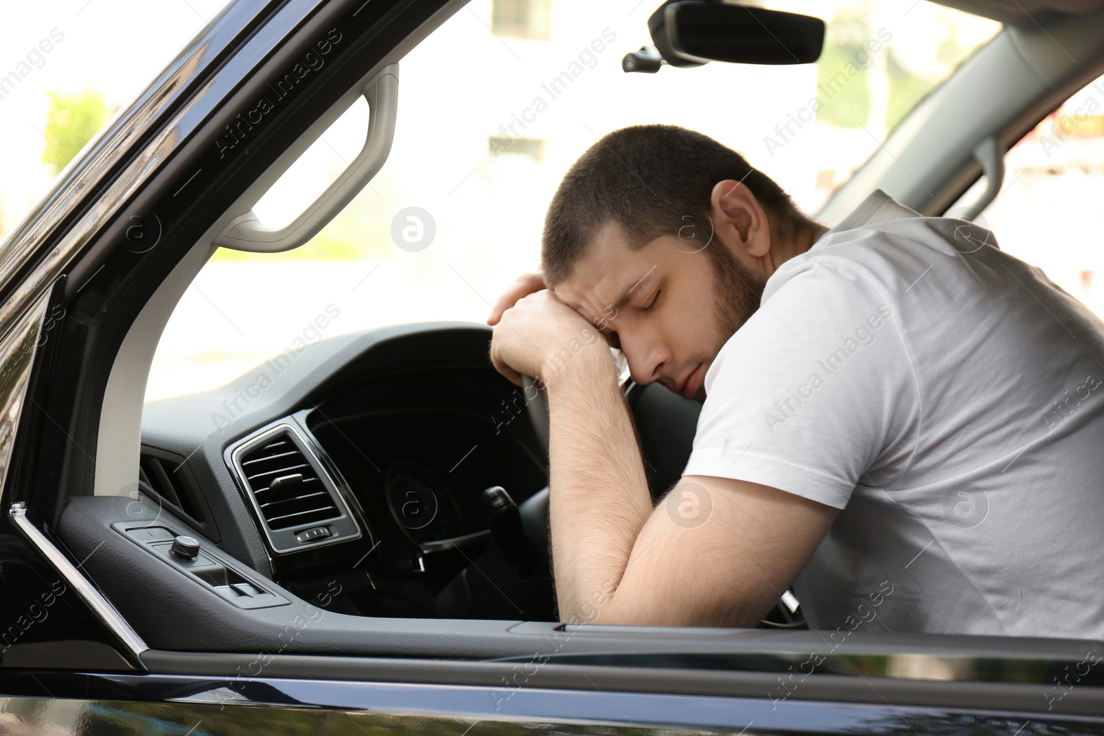 Photo of Tired man sleeping on steering wheel in his car