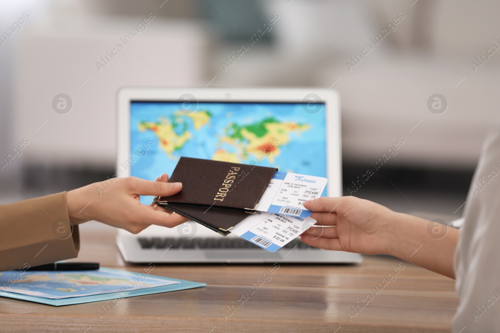 Photo of Travel agent giving tickets and passports to client in office, closeup