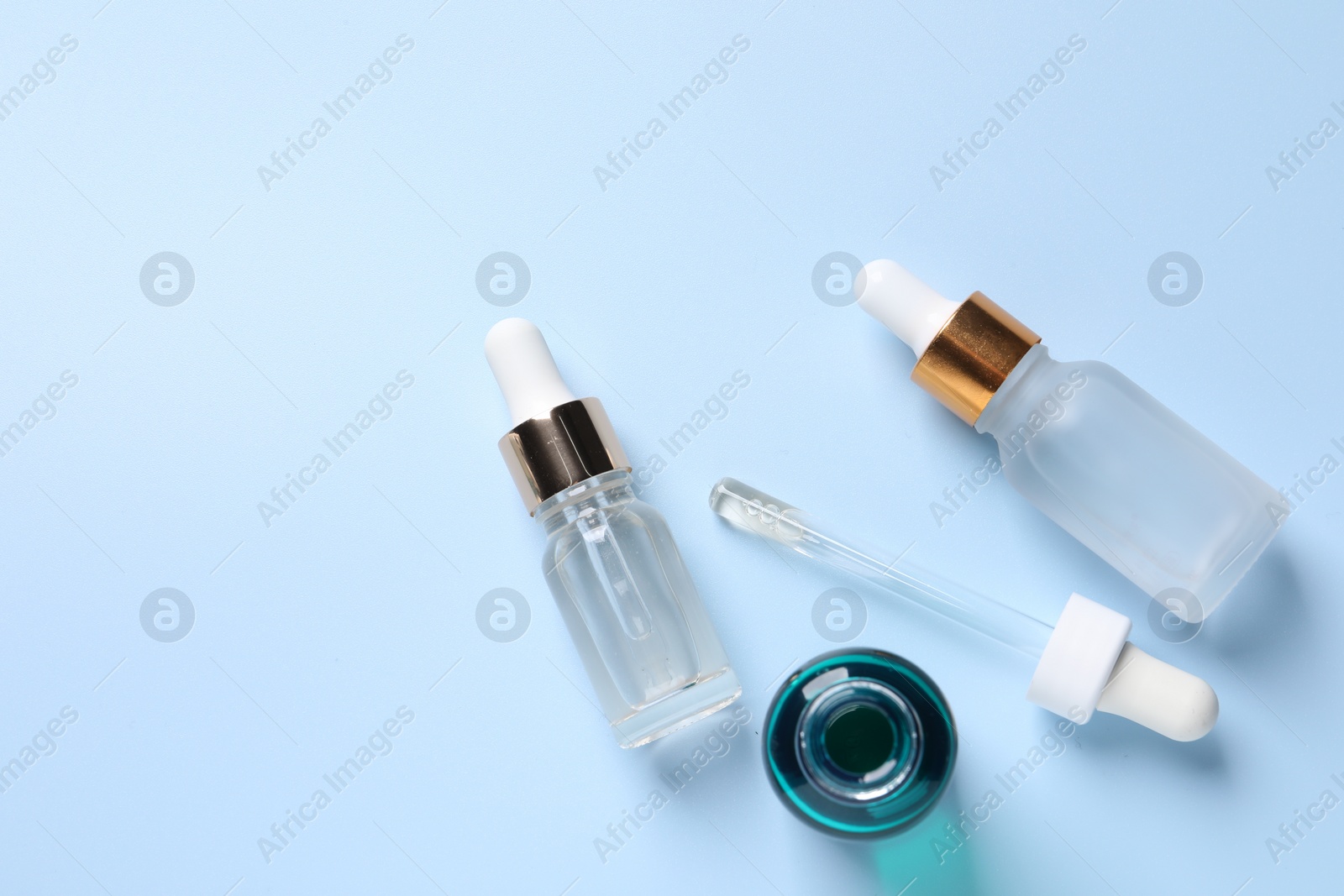 Photo of Bottles of cosmetic serum on light blue background, flat lay. Space for text