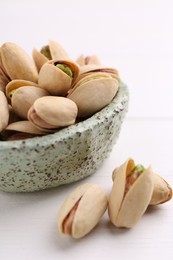 Delicious pistachios in bowl on white table