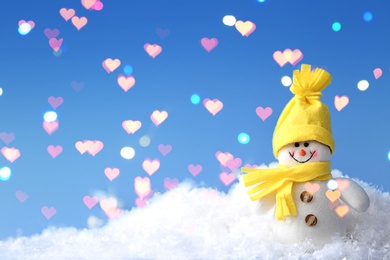 Image of Cute snowman in snow against blue background, bokeh effect. Space for text 