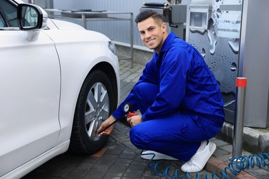 Photo of Professional mechanic inflating tire at car service